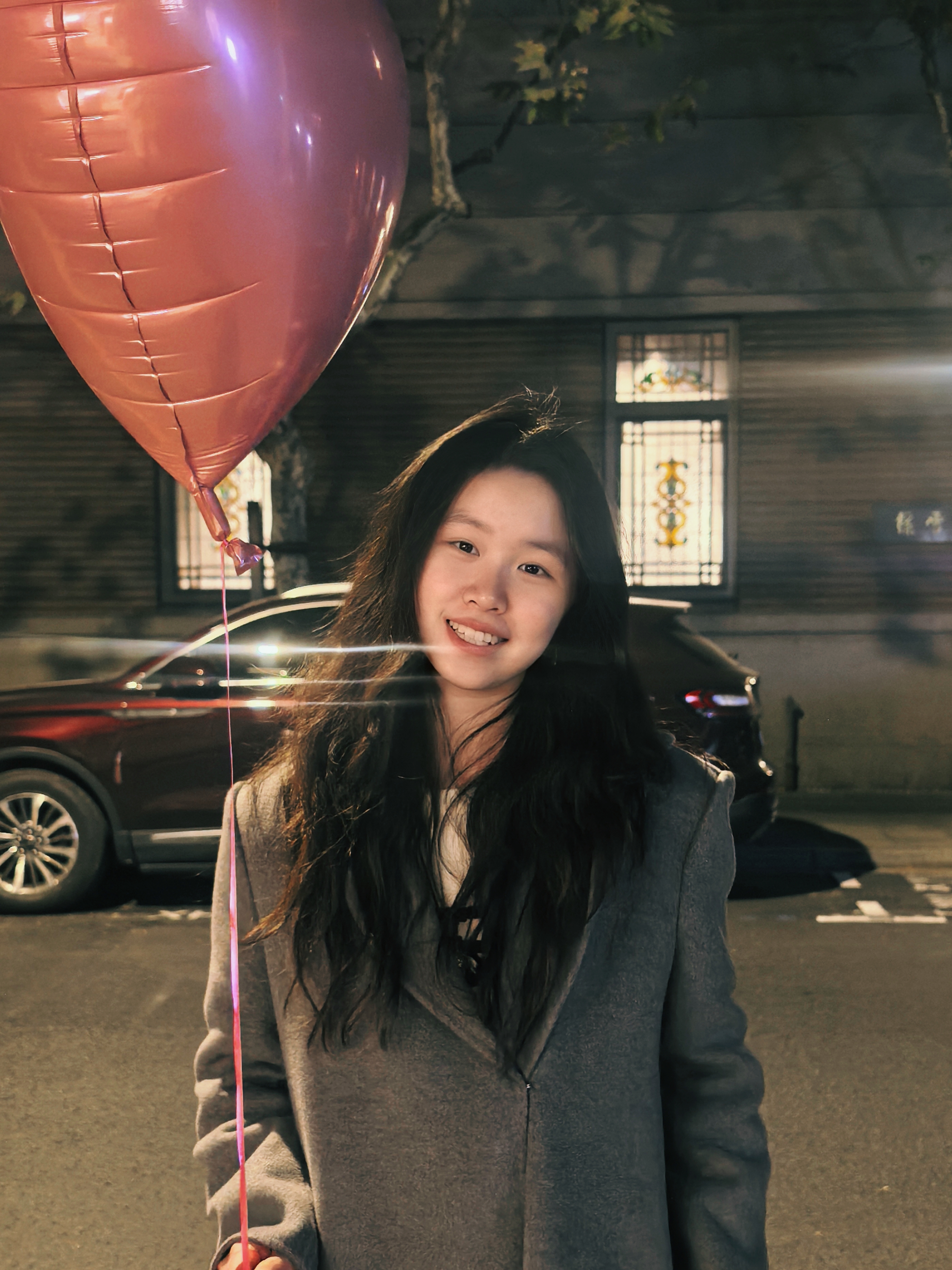 Yueyang Tang holding a balloon outdoors at night